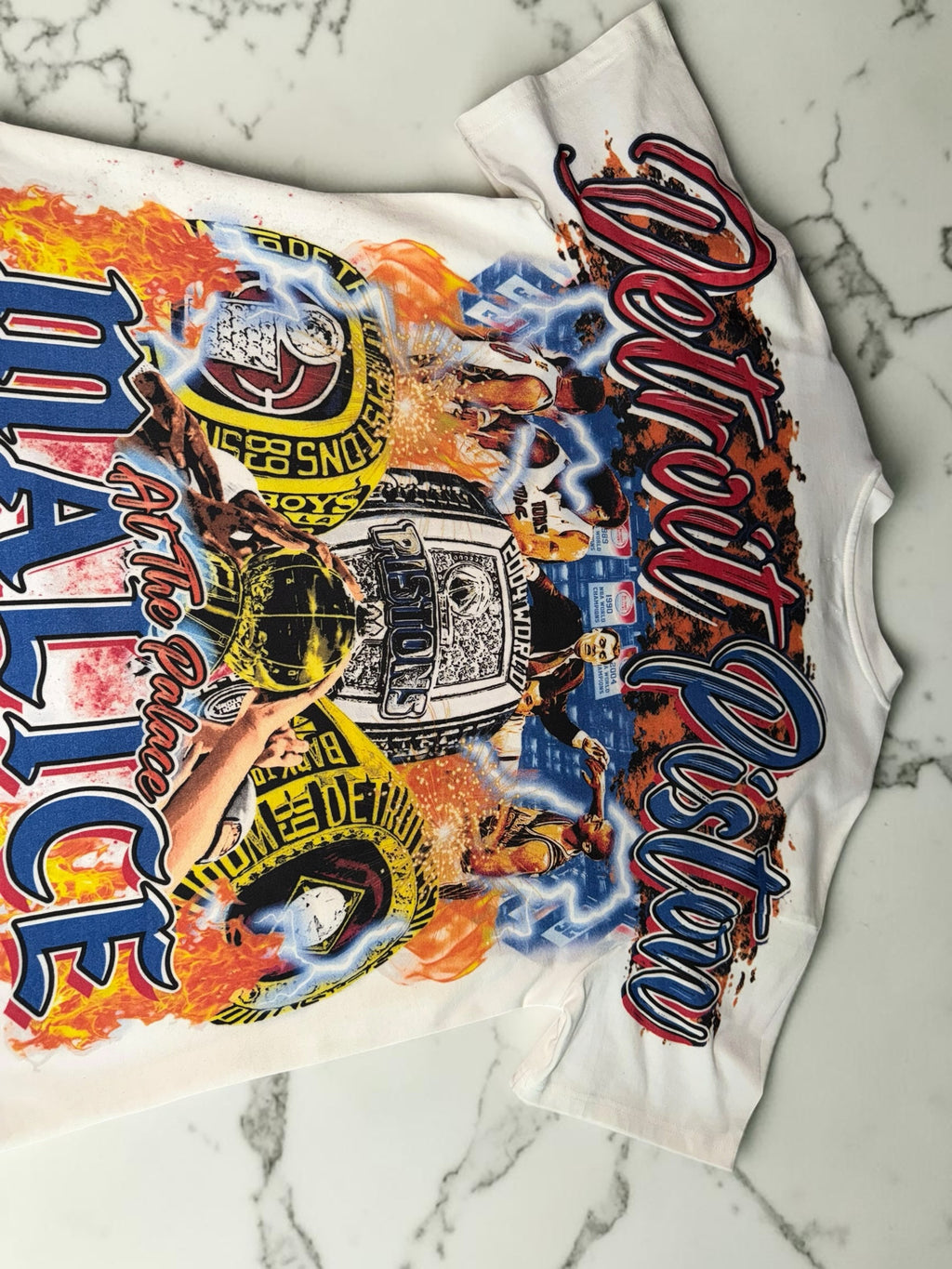 DRIPPING IN VINTY off-white Detroit Pistons graphic t-shirt featuring vintage basketball championship ring prints.
