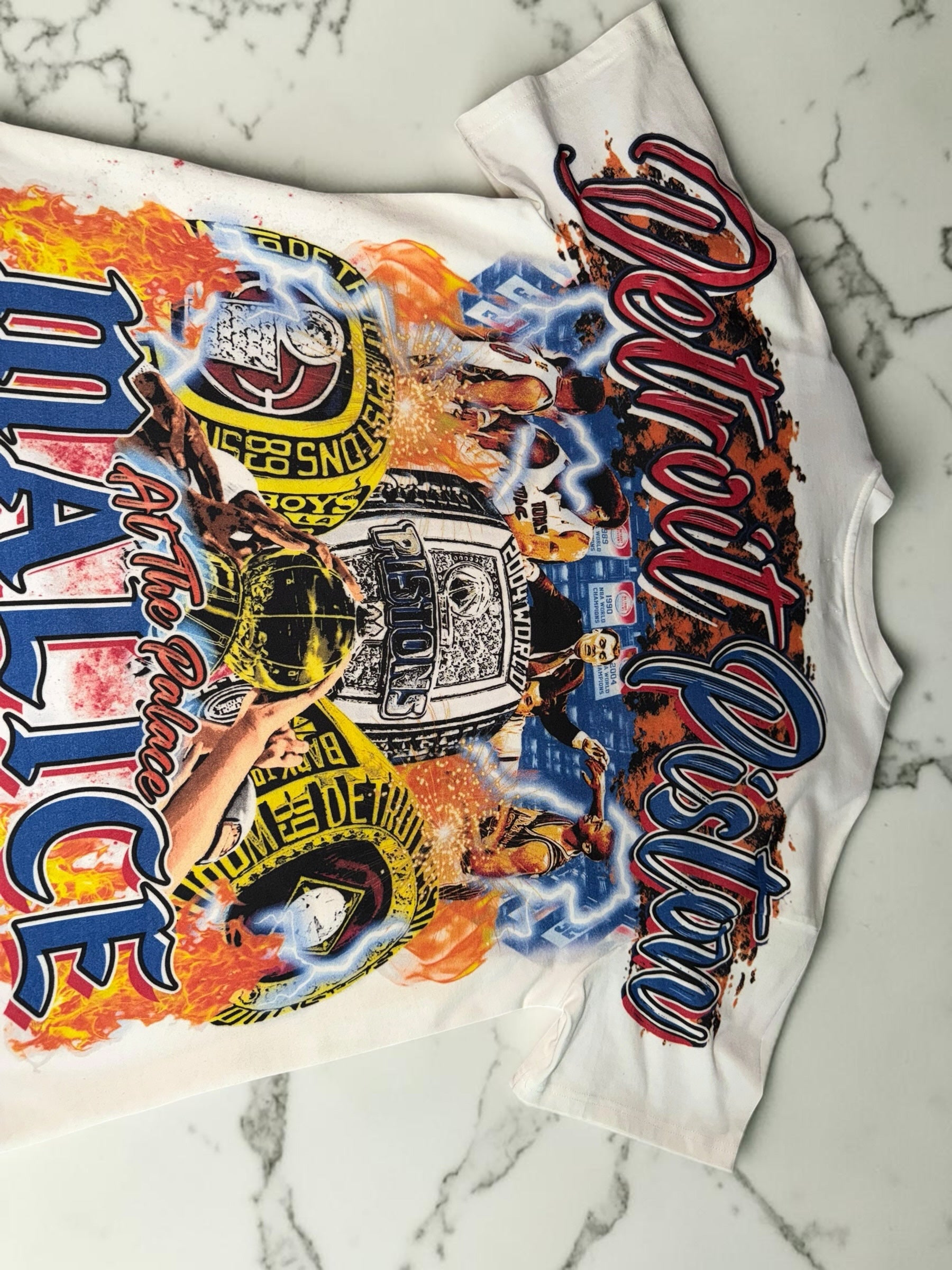 DRIPPING IN VINTY off-white Detroit Pistons graphic t-shirt featuring vintage basketball championship ring prints.